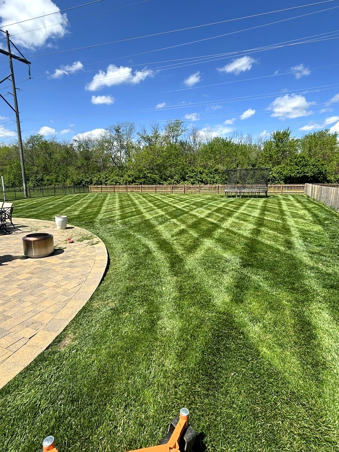 A beautifully landscaped backyard garden at golden hour with stone pathways, lush lawn, and outdoor lighting